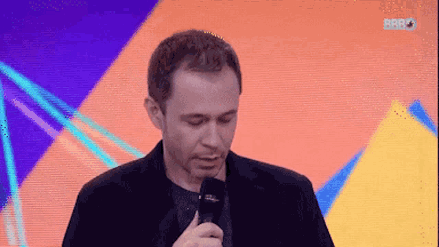 a man in a suit holds a microphone in front of a screen that says bbbo