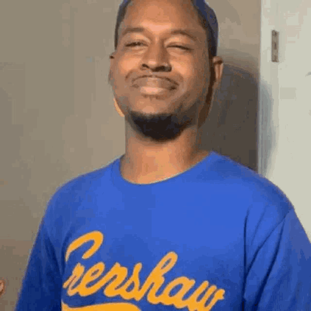 a man wearing a blue and yellow t-shirt is smiling and looking at the camera .