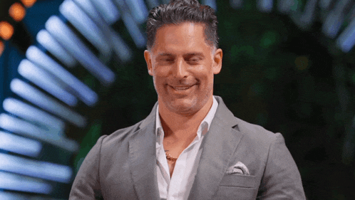 a man in a suit and white shirt smiles with his eyes closed