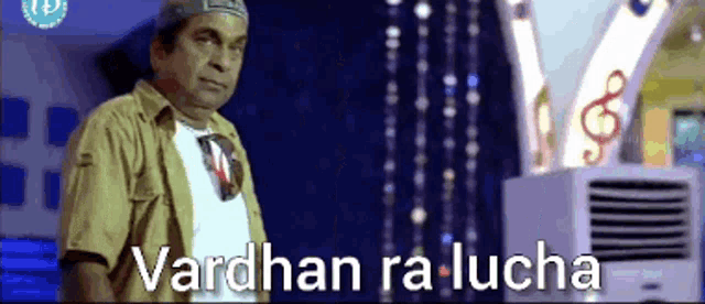 a man in a hat is standing in front of an air conditioner with the words vardhan ra lucha written on it .