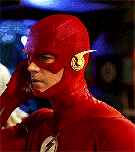 a man in a flash costume is talking on a phone
