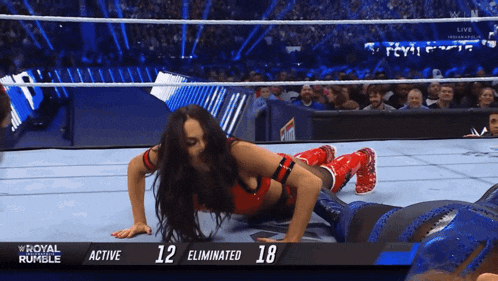 a female wrestler is doing push ups in a wrestling ring with the numbers 12 and 18 behind her