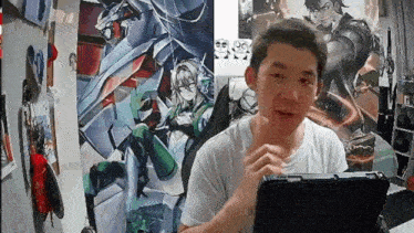 a man is sitting in front of a laptop computer in front of a wall with a picture of a robot on it .