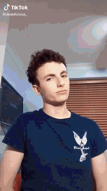 a young man wearing a blue t-shirt that says bling angel