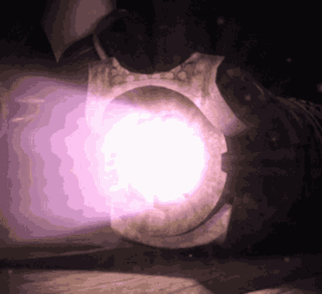 a purple light is coming out of a metal object in the dark