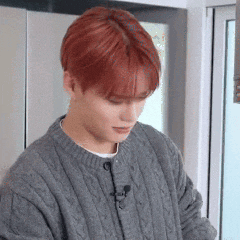 a young man with red hair is wearing a gray sweater .
