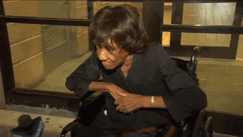 an elderly woman in a wheelchair is looking out a window