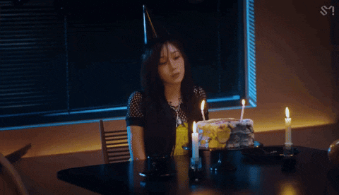a woman sitting at a table with a birthday cake and candles .