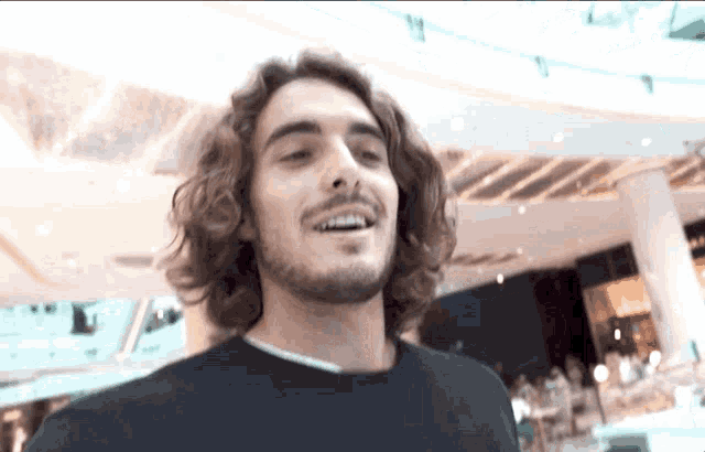 a man with curly hair and a beard is smiling