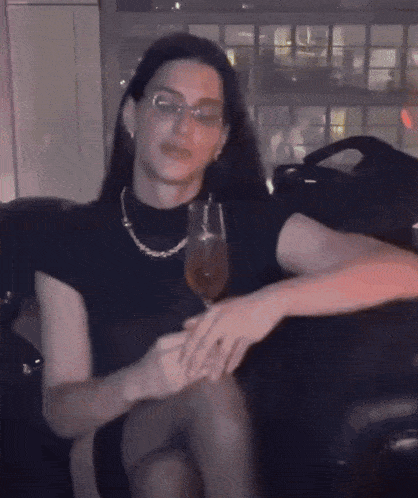 a woman sitting on a couch with a glass of wine in her hand