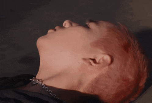 a close up of a person with red hair and a silver chain around their neck