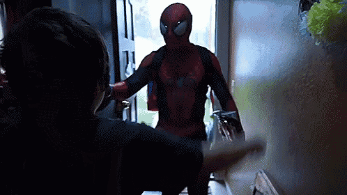 a man in a spiderman costume is standing in front of a door