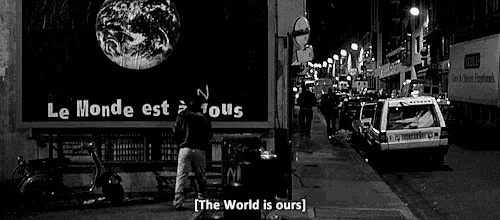 a black and white photo of a street with a sign that says " the world is ours "