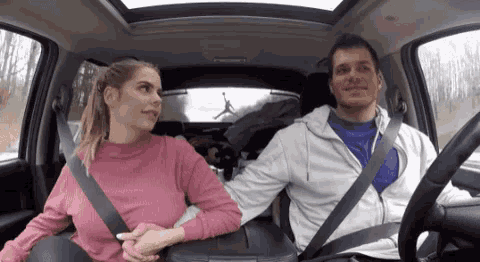 a man and a woman are holding hands in the back seat of a car .