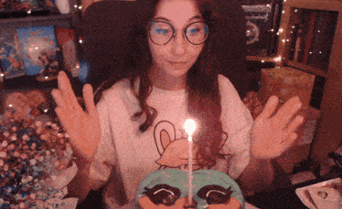 a girl wearing glasses is blowing out a candle on a cake