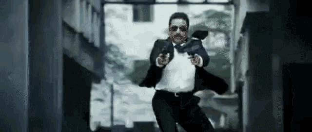 a man in a suit and tie is pointing a gun at someone .
