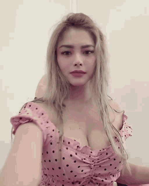 a woman in a pink polka dot dress takes a picture of herself