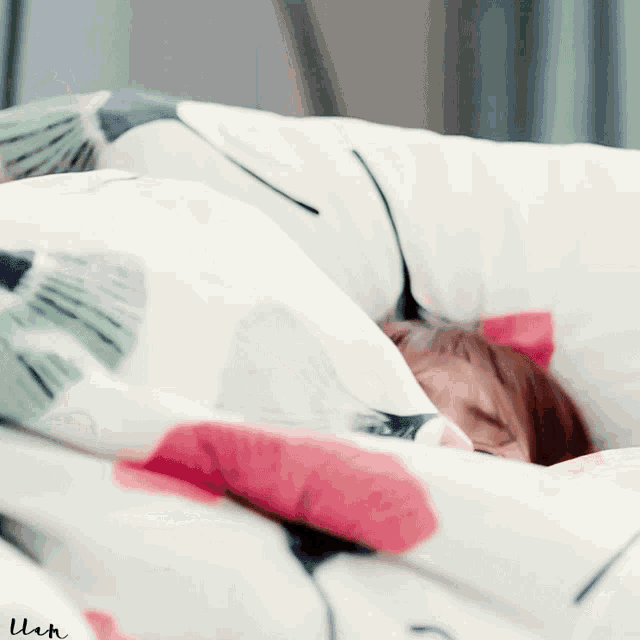 a person laying under a blanket with the letter u on the bottom left