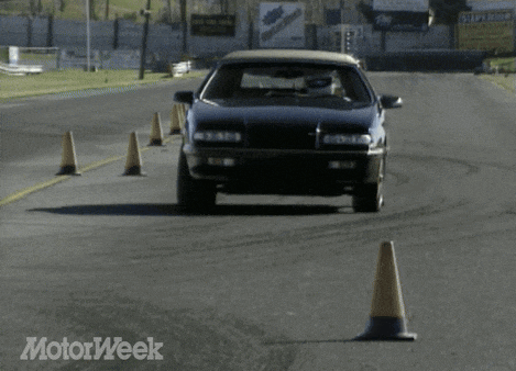 a black car is driving on a road with a motorweek logo in the corner