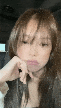 a close up of a woman 's face with a hand on her chin