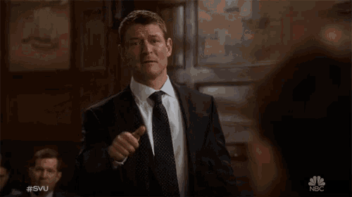 a man in a suit and tie is pointing at another man with the hashtag #svu on the bottom