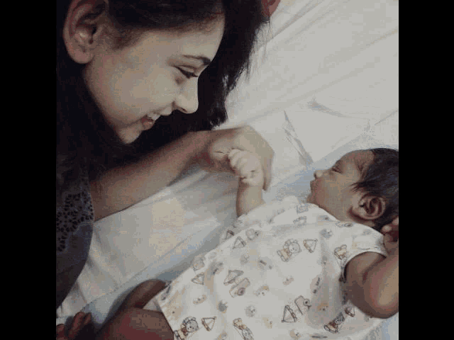 a woman is holding a baby 's hand and the baby is wearing a shirt that says 40