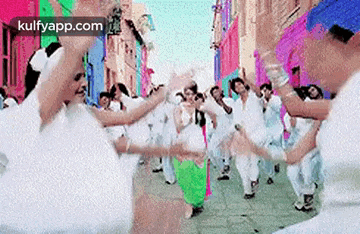a group of people are dancing in a parade in a city street .