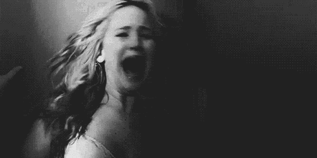 a black and white photo of a woman with her mouth open .