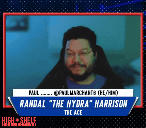a man with a beard and glasses sits in front of a screen that says randal " the hydra " harrison