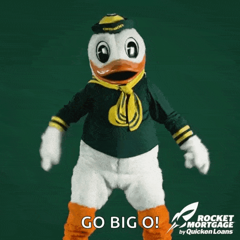 a duck mascot is dancing in front of a green background and says go big o .