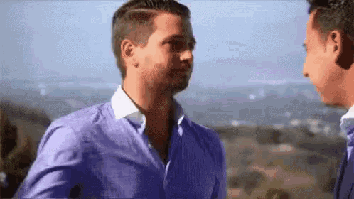 two men in blue shirts are standing next to each other .