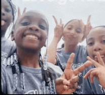 a group of young girls are giving the peace sign and smiling