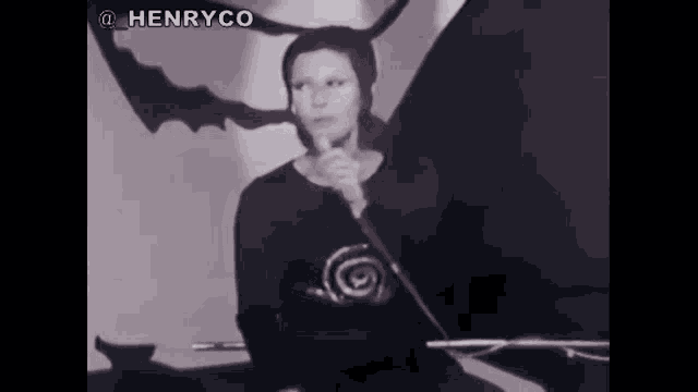 a woman with horns is singing into a microphone in a black and white photo