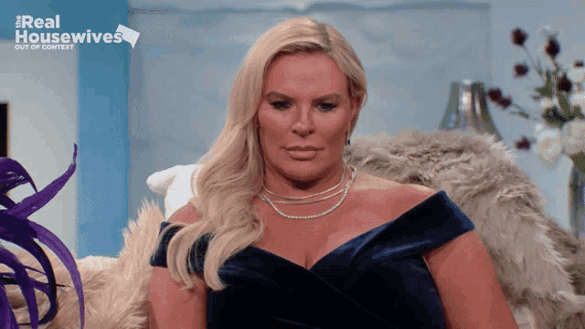 a woman is sitting on a couch with the words real housewives out of context behind her