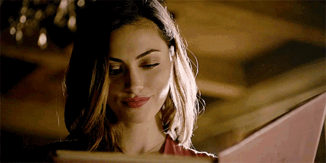 a woman is reading a book with her eyes closed and smiling .