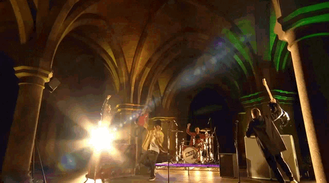 a group of people playing instruments in a dark room with a drum set that says ' nct ' on it