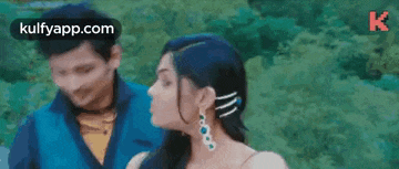 a man and a woman are standing next to each other . the woman is wearing earrings .