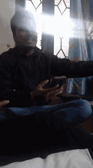 a man in a black jacket holds a cell phone