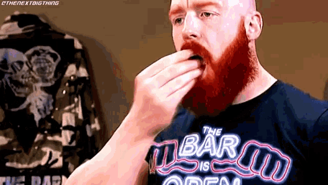 a man with a red beard is wearing a shirt that says the bar is open .