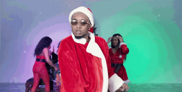 a man dressed as santa claus is standing in front of two women