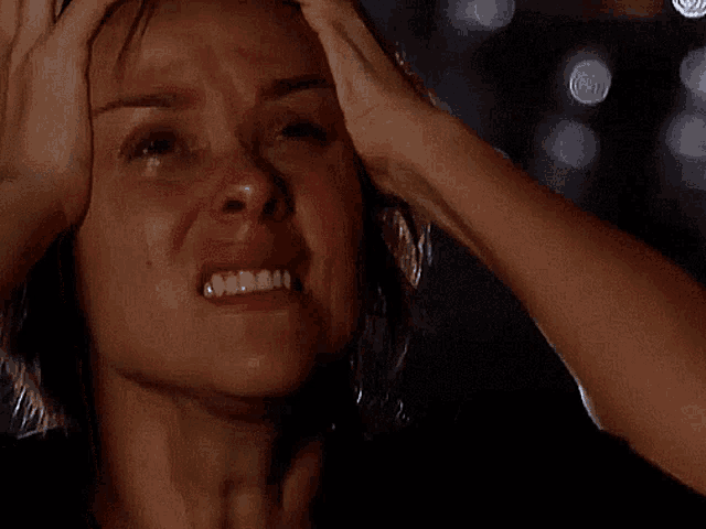 a woman is crying and holding her head in pain
