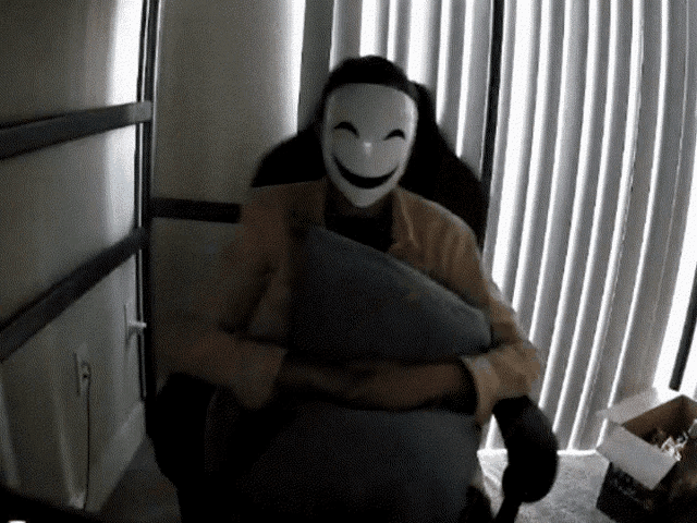 a person wearing a mask holds a pillow