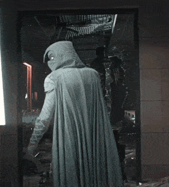 a person in a white cape stands in a doorway
