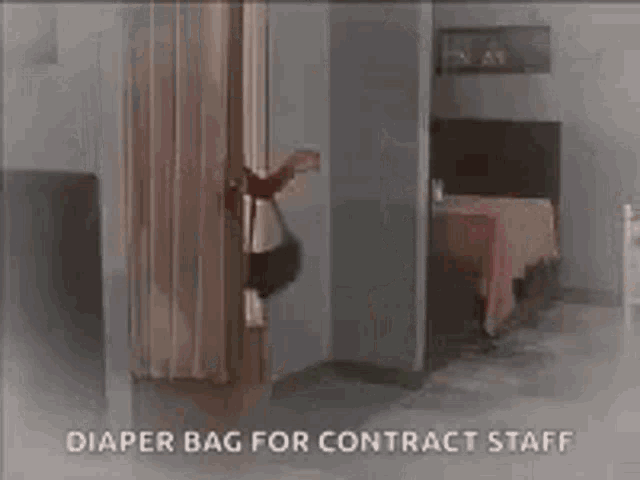 a woman is carrying a diaper bag for contract staff while standing in a room .