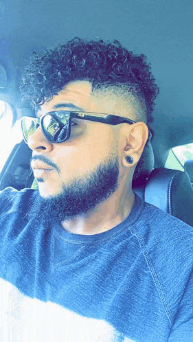 a man with curly hair and a beard is wearing sunglasses and ear plugs