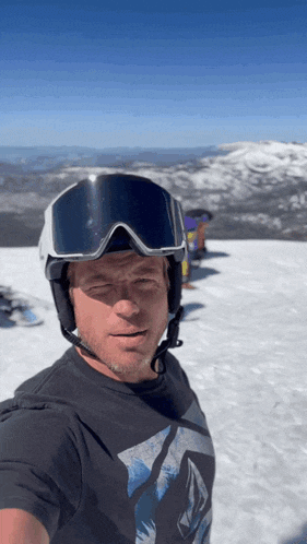 a man wearing a helmet and goggles on top of a snowy mountain