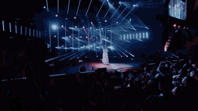 a woman singing into a microphone on a stage with a lot of lights behind her