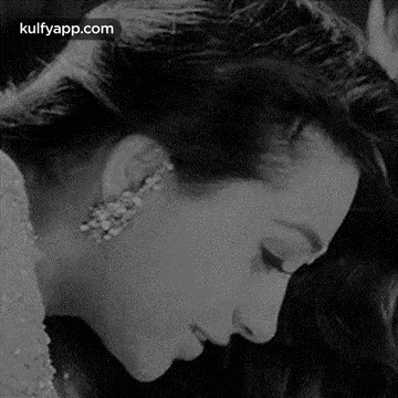 a black and white photo of a woman wearing earrings and a crown .