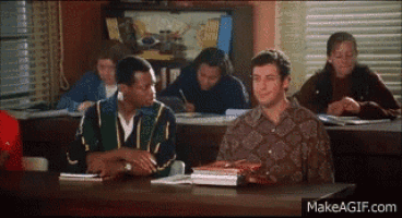 a group of people are sitting at desks in a classroom with makeagif.com in the corner