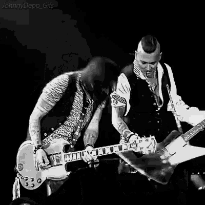 two men are playing guitars on a stage .